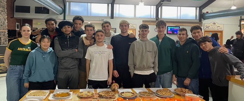 group of students standing behind table full of pies